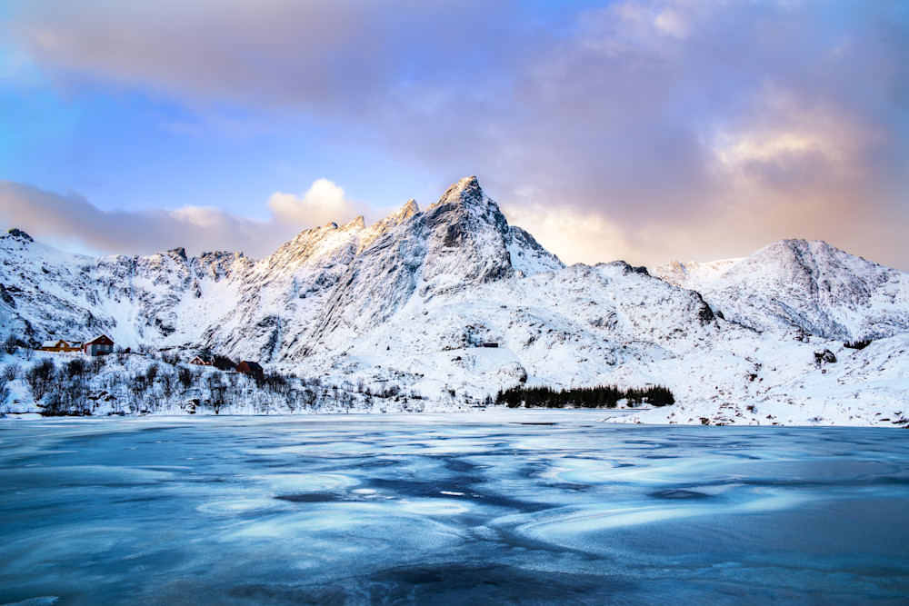 The sun rises on Norway's Skottinden mountain on the Lofoten Archipelago with an icy lake in the front
