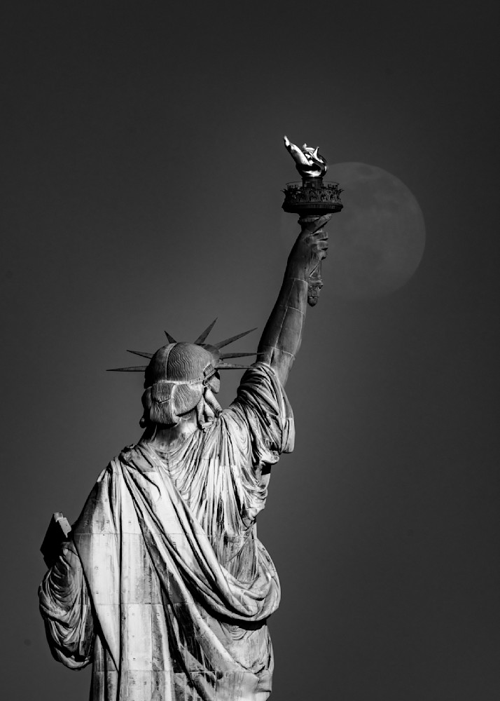 full moon rising over statue of liberty