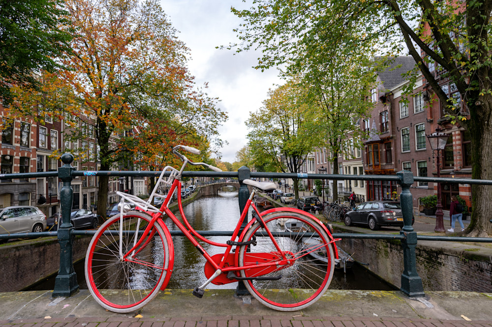 Red bicycle parked on a bridge over a canal in Amsterdam
