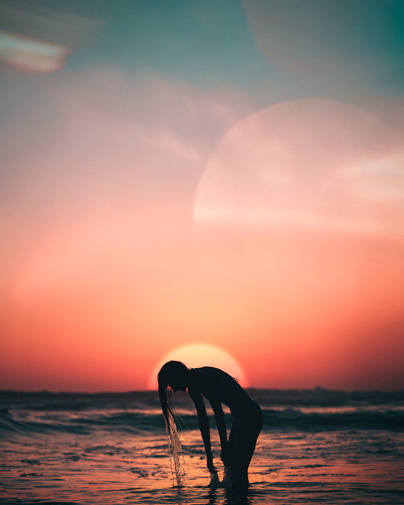 Woman in the ocean at sunset with dripping wet hair