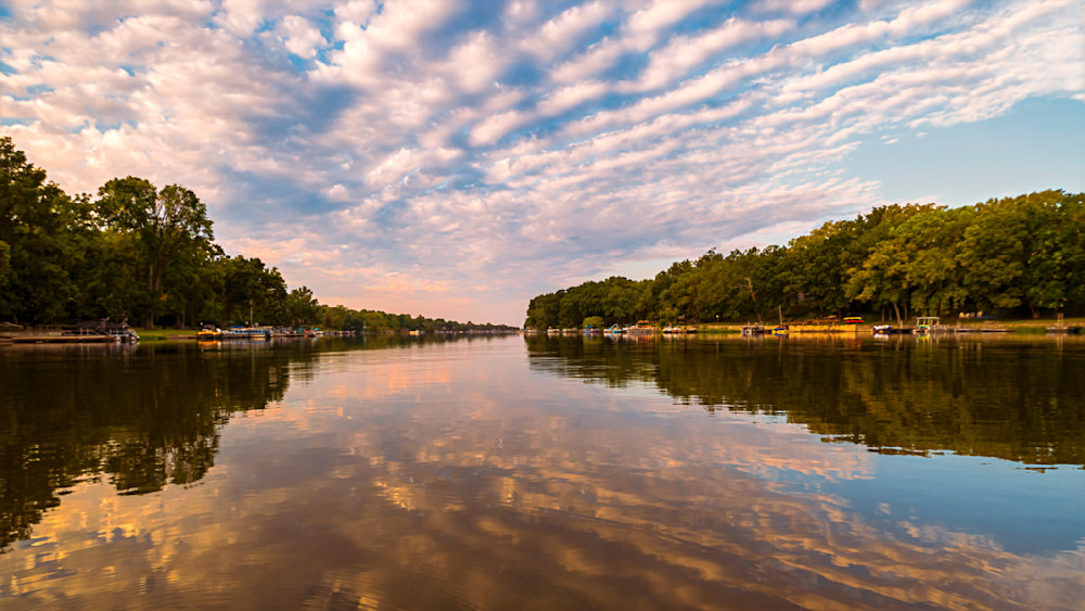 Scenic view of a calm lake with reflections and textured clouds at sunset