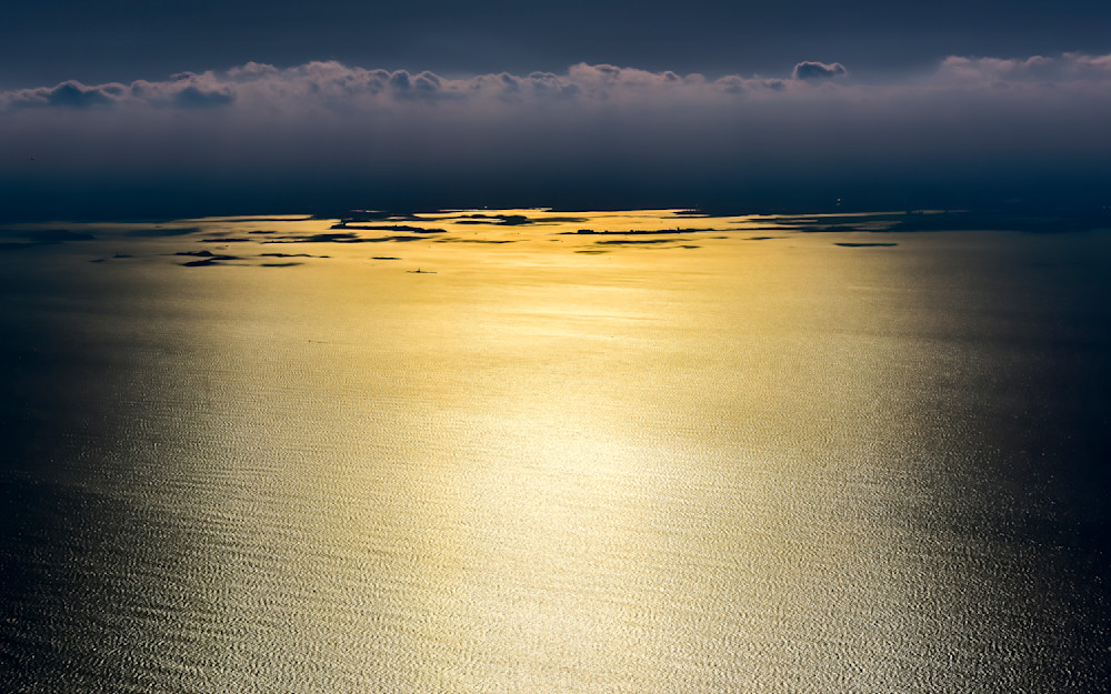 Golden calm over Boston Harbor reflecting the sun's light on tranquil waters during a clear day