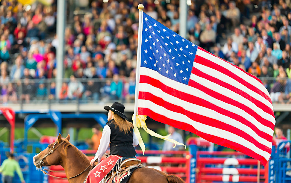 American Sweetheart showcases patriotism before the rodeo's first bronc ride with a flag bearer on horseback