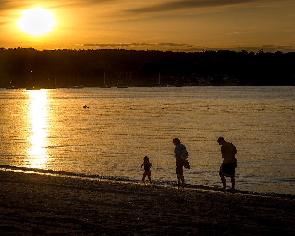 Family walking along a Rhode Island beach during sunset near the water's edge