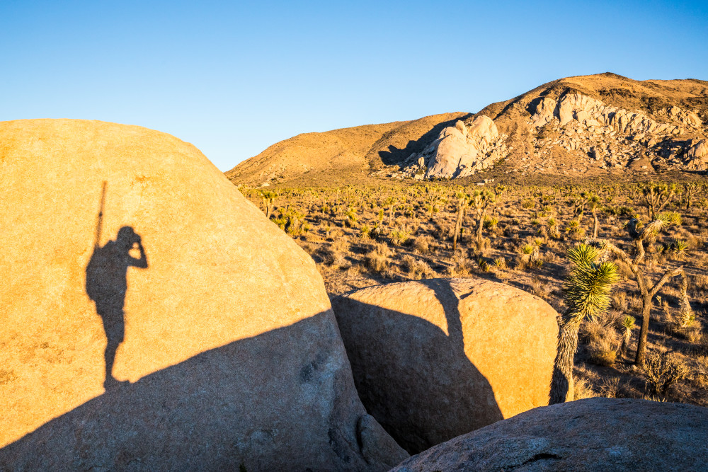 The shadow of a man cast on a boulder while he is taking a picture in Joshua Tree National Park.
