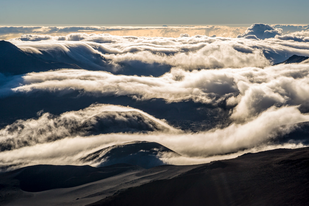 Clouds flowing over Haleakala crater and surrounding mountains as seen from atop Haleakala, Maui, Hawaii, USA.