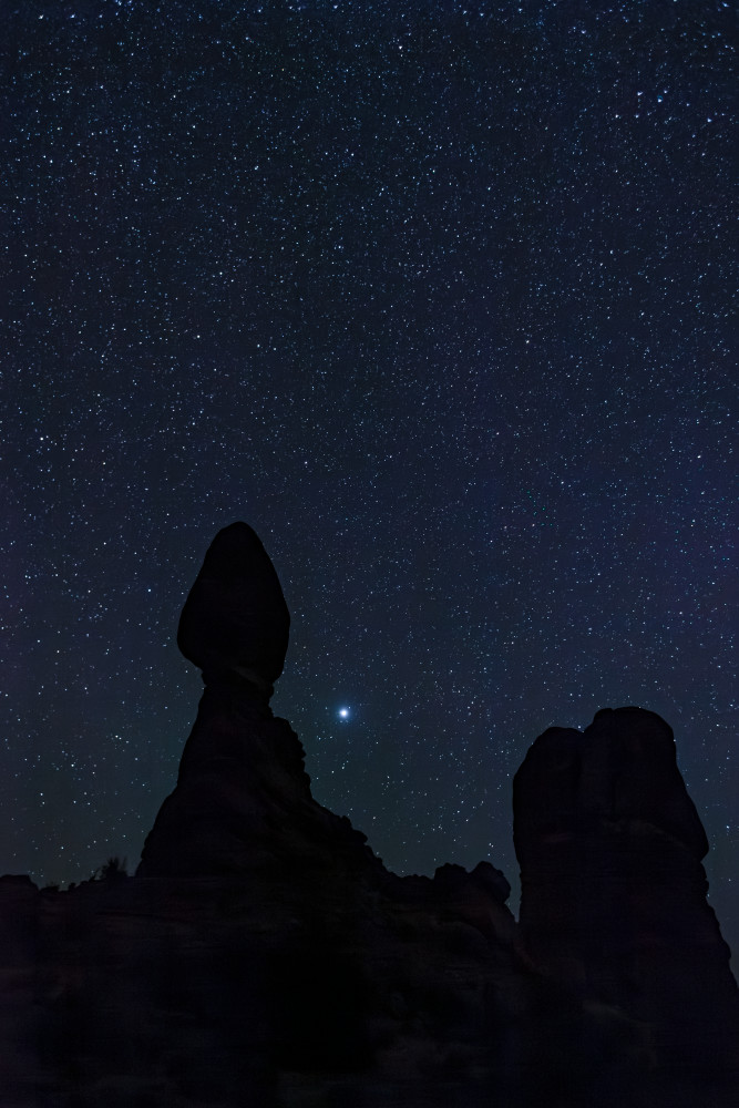 Balanced Rock in Arches National Park at night with a starry night sky in the background, Utah, USA. Jupiter shines bright near center bottom.