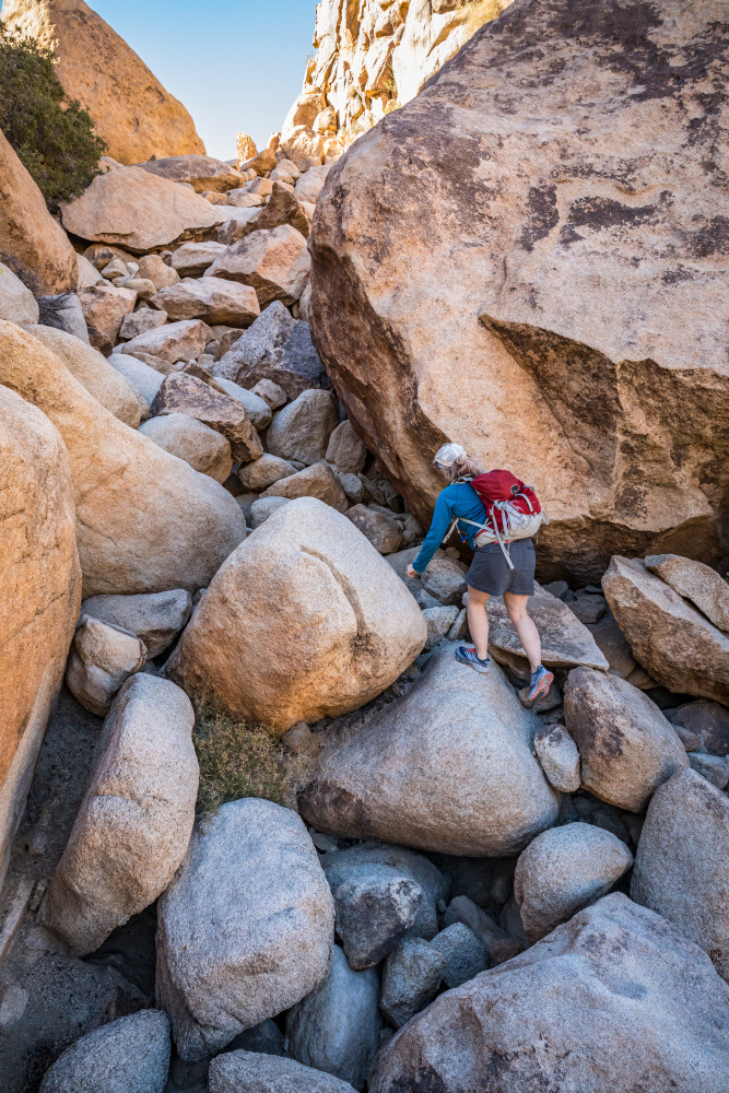 A woman scrambing over the boulders in Rattlesnake Canyon in Joshua Tree National Park.
