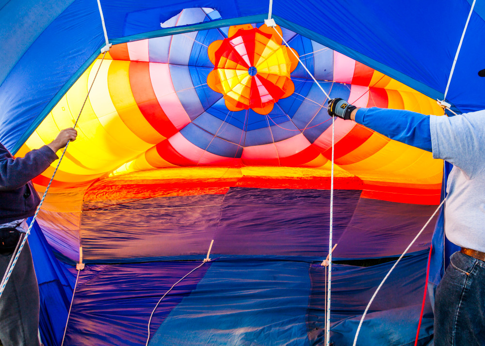Two men holding the balloon open as it fills up with air.  Albuquerque, New Mexico, USA.