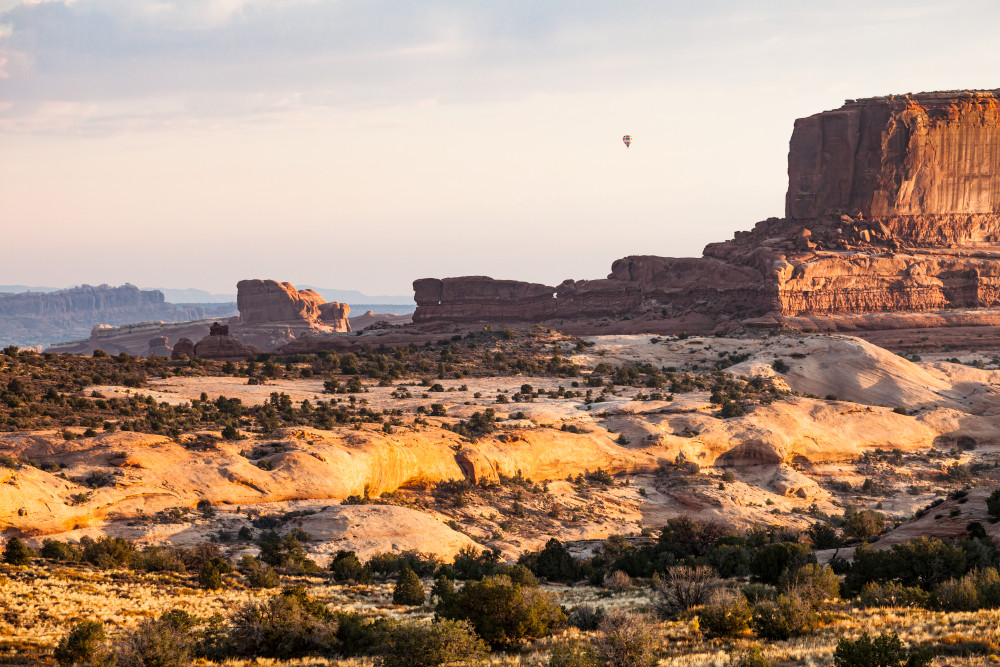 Sunrise and a hot air balloon over the desert landscape Northwest of Moab, Utah, USA.