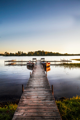 Boat dock lake side resort john boats fishing boats lake front sunset vertical color water s edge vacation summer time fishing season calm water glassy oealol
