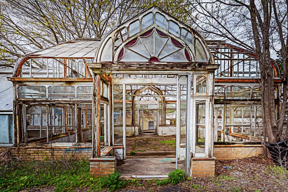 An abandoned greenhouse behind an old mansion