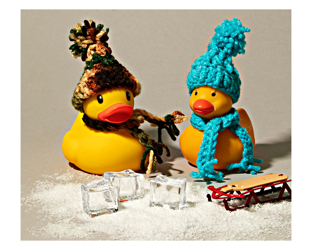 two rubber ducks with crocheted hats and scarves