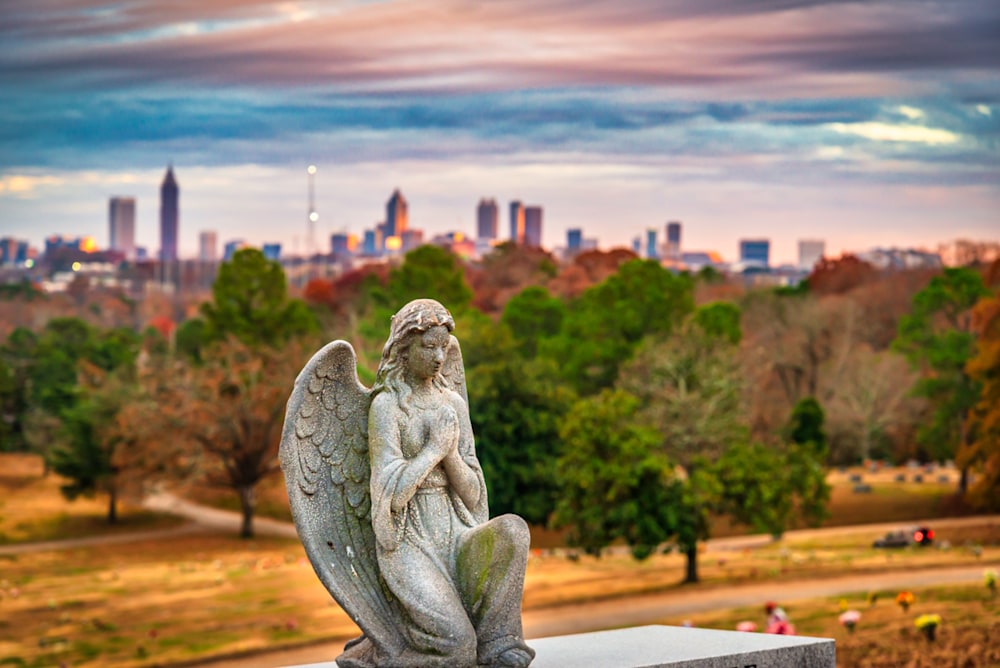 A concrete angel in a prayer pose with the City of Atlanta in the background