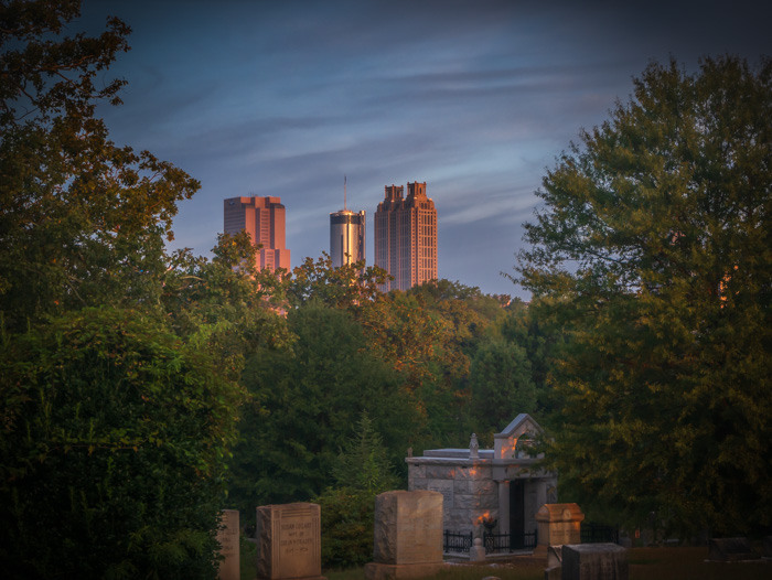 A photo of some tall Atlanta buildings with some headstones from a cemetery in the foreground