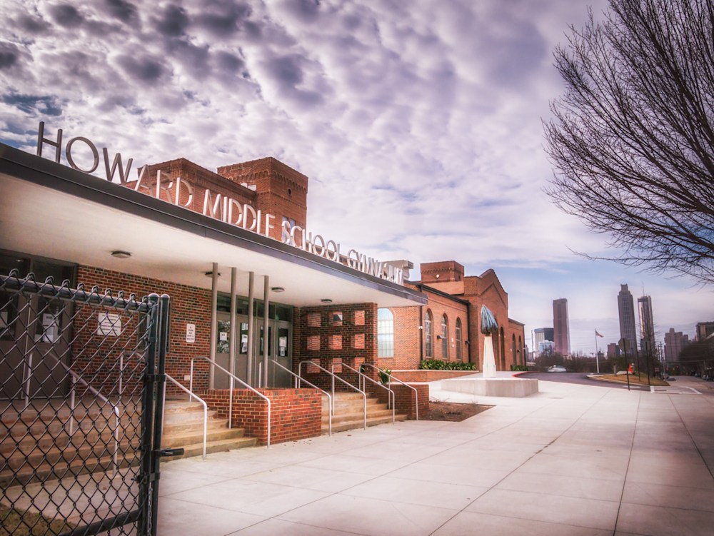 A photo of the Howard Middle School Sign over the gym at Howard Middle School with beautiful clouds and the city way in the background