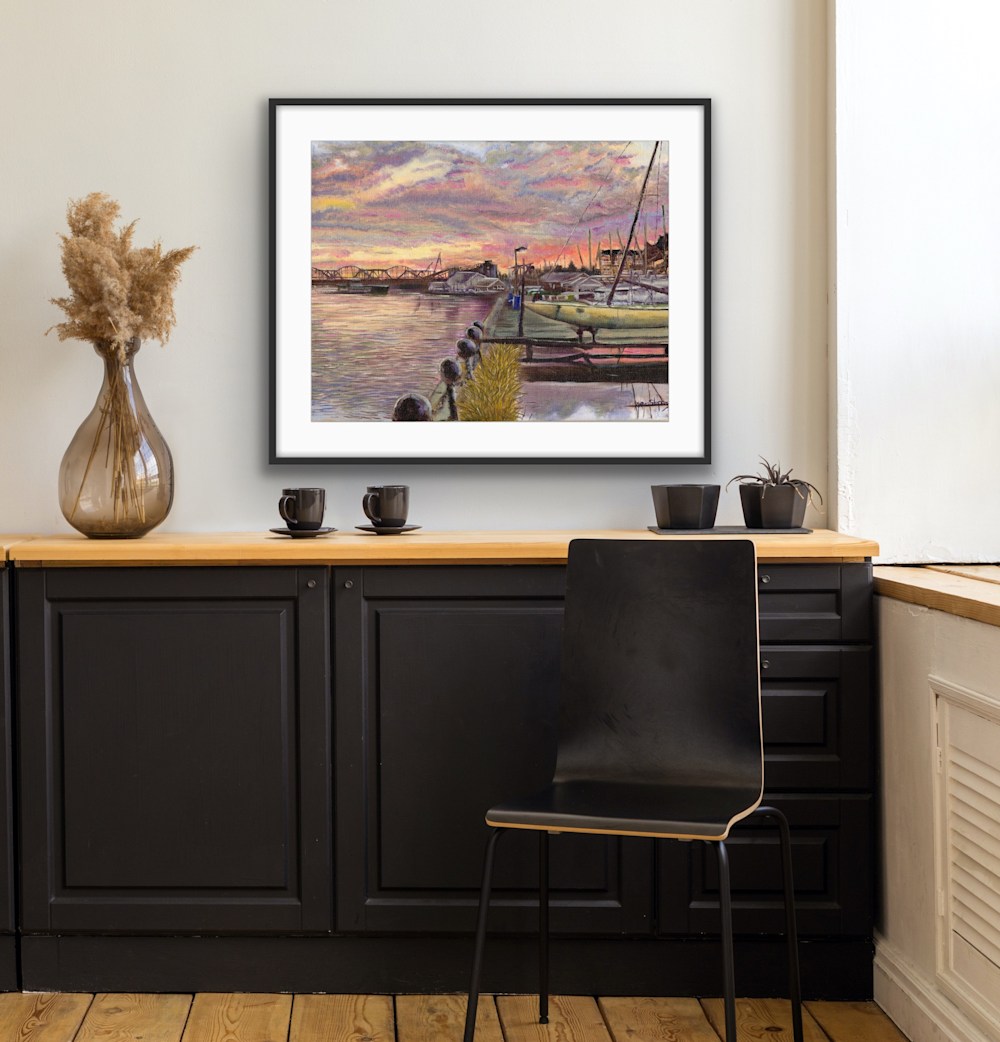 A painting on display of the Davenport Sailing Club with the Government Bridge and the Centennial bridge silhouetted by an Iowa Sunset along the Mississippi River in Davenport Iowa created by Blue Grass native oil painter, Marie Stephens