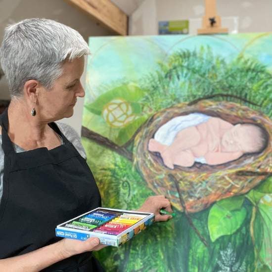 Artist Fran Cooper painting at her easel, creating vibrant colorful art for jolly, cozy spaces.