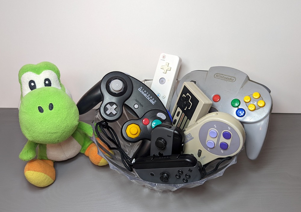 Still life setup includes a variety of video game controllers and a Yoshi plush.