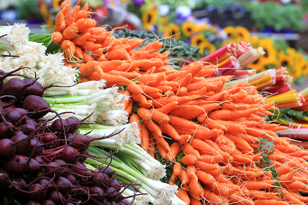 Fresh organic carrots, green onions, and beets at a colorful local farmers market