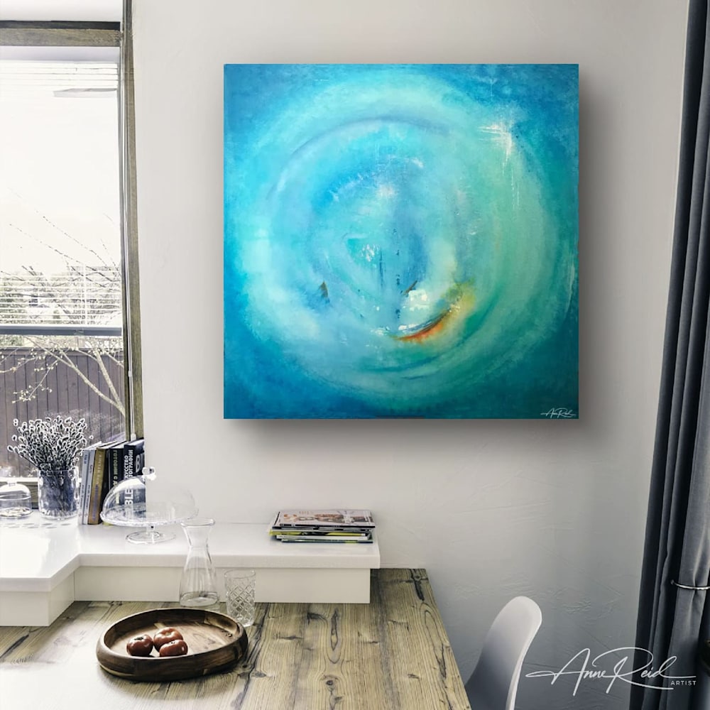 Soothing abstract art in oceanic blues and turquoise tones above rustic wood desk in light-filled room