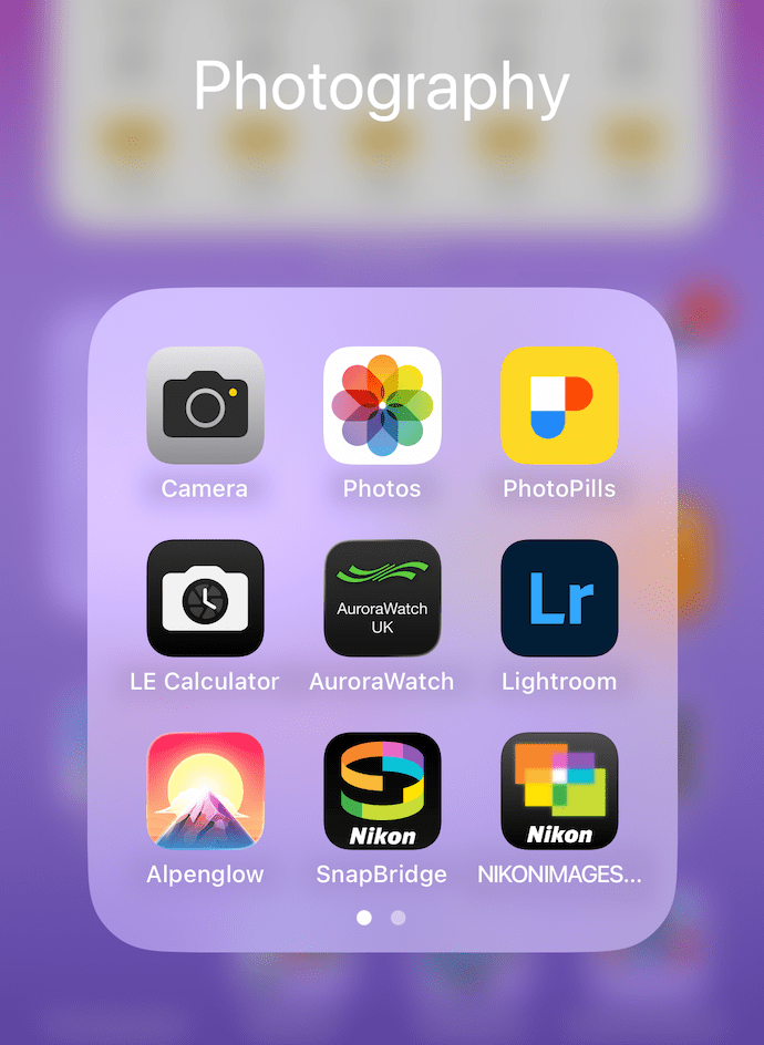 A phone screen showing a folder labelled Photography, containing app icons for Camera, Photos, PhotoPills, LE Calculator, AuroraWatch UK, Lightroom, Alpenglow, and two Nikon-branded apps.