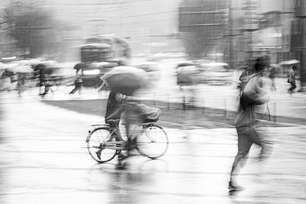 Man walking a bicycle through storm rain while layered, ghosted figures with umbrellas move across him in opposing motion streams.