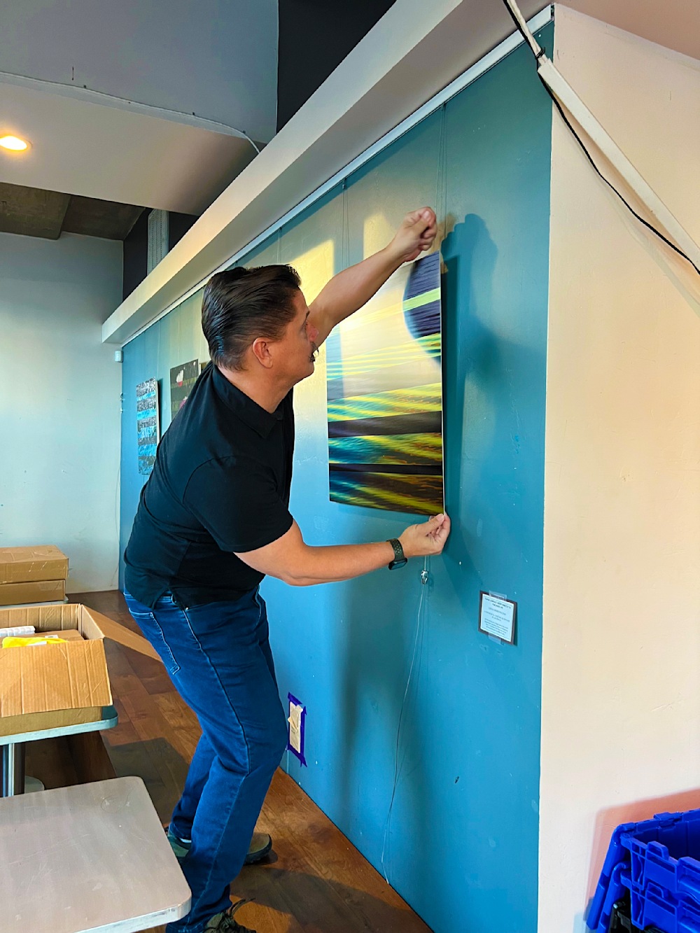 Artist Jon Savage installing 'Golden Reflections' original textured metal wall art at Bird Rock Coffee in Little Italy, San Diego.