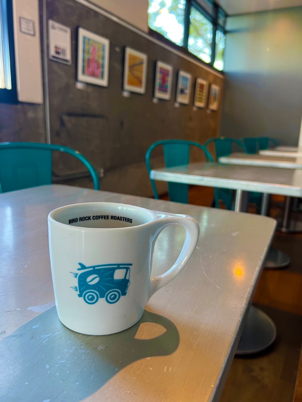 A lifestyle view of a coffee mug with Jon Savage's fine art print collection at Bird Rock Coffee, capturing the Little Italy gallery experience.