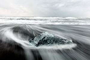 Iceberg on black sand with streaking surf – Glacier Lagoon, Iceland